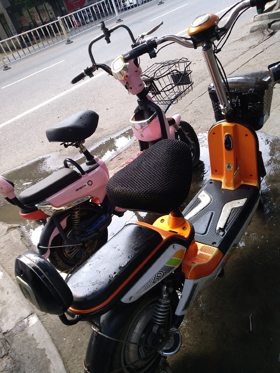 出两辆爱玛电动车实拍图，人和地铁口附近看车