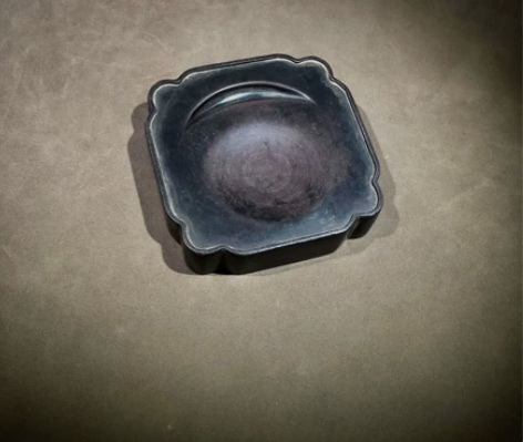 端砚，正方形，墨池作弯月形，砚面周缘有凸起...